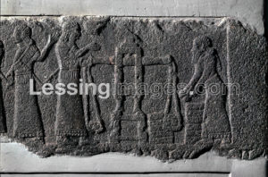 The Rassam obelisk from Nimrud, Mesopotamia, northern Iraq. Neo-Assyrian, 883-859 BCE. This fragment of a stone relief formed part of an obelisk discovered by archaeologist Hormuzd Rassam. The obelisk decorated one of the central squares in Nimrud, the site where King Ashurbanipal II chose to build his new administrative centre of the Assyrian Empire. This panel shows the king watching treasure being weighed on a pair of scales. ANE, 118800.